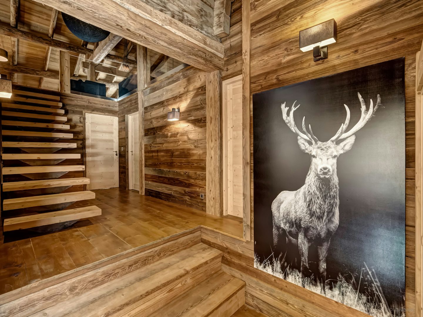 The stairwell at Chalet Victorina with a large stag head image and wooden interiors.