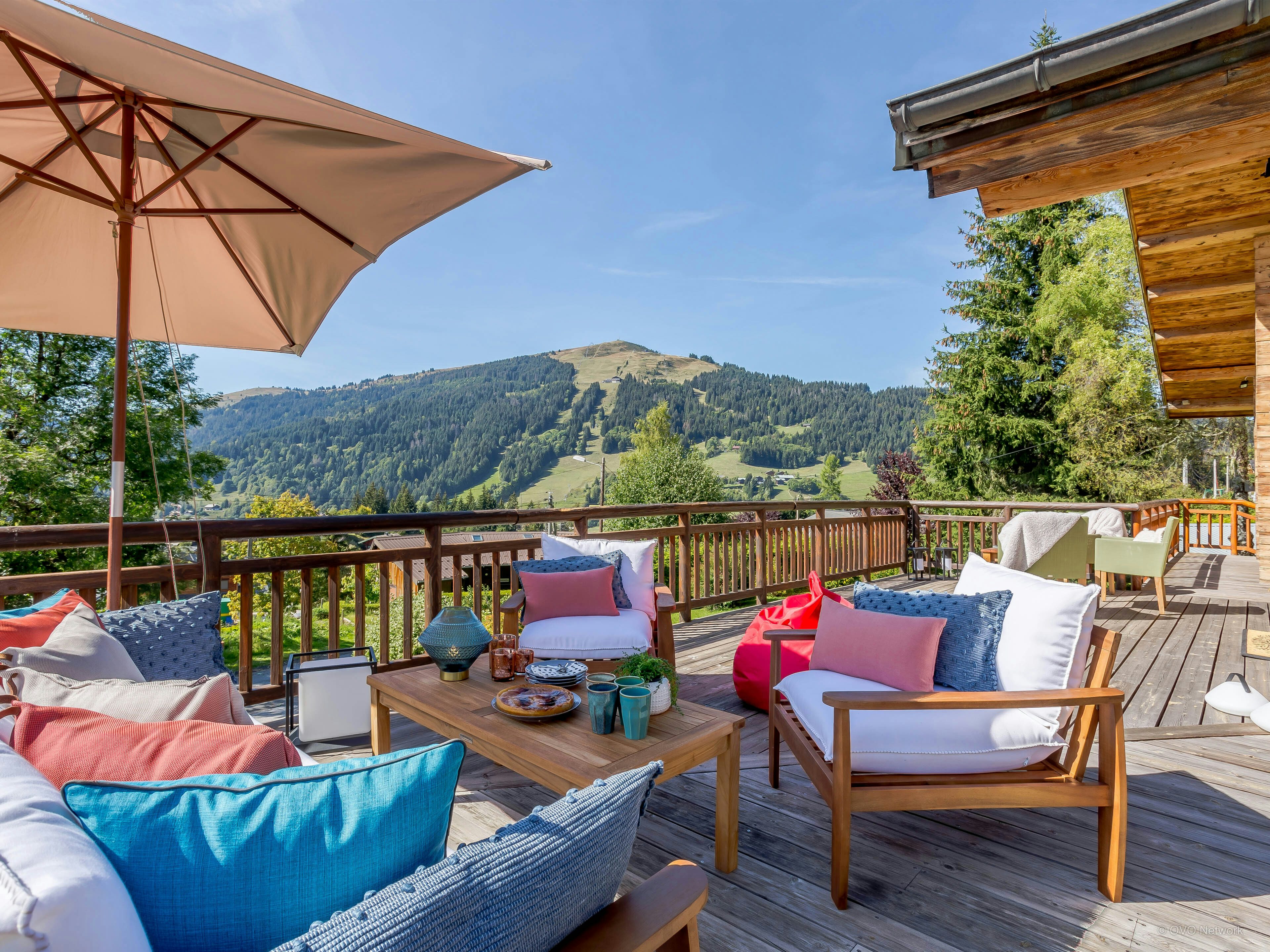 The mountain view from the terrace at Chalet Joux Verte, with chairs and a sofa covered in cushions and throws